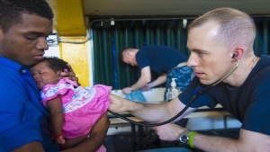 Bryan, assigned to Naval Medical Center Portsmouth, Va., examines a patient at a medical site established at Coliseo Del Centro during Continuing Promise 2015.  