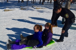 Roanoke Rapids police officer Alex Green gives sledders a boost at T.J.Davis today.