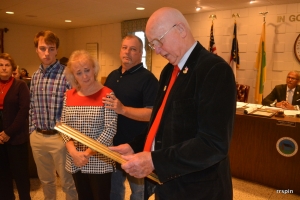 Manning reads the framed resolution to Isles, as her husband, David, stands behind her for support and their son, Sammy, and Hux&#039;s sister, Joan Webster, look on.